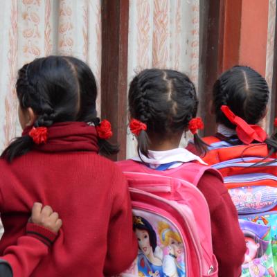 Students in Nepal wait patiently in a line for their Childcare volunteer. Children line up with their backpacks outside their classroom in Nepal.